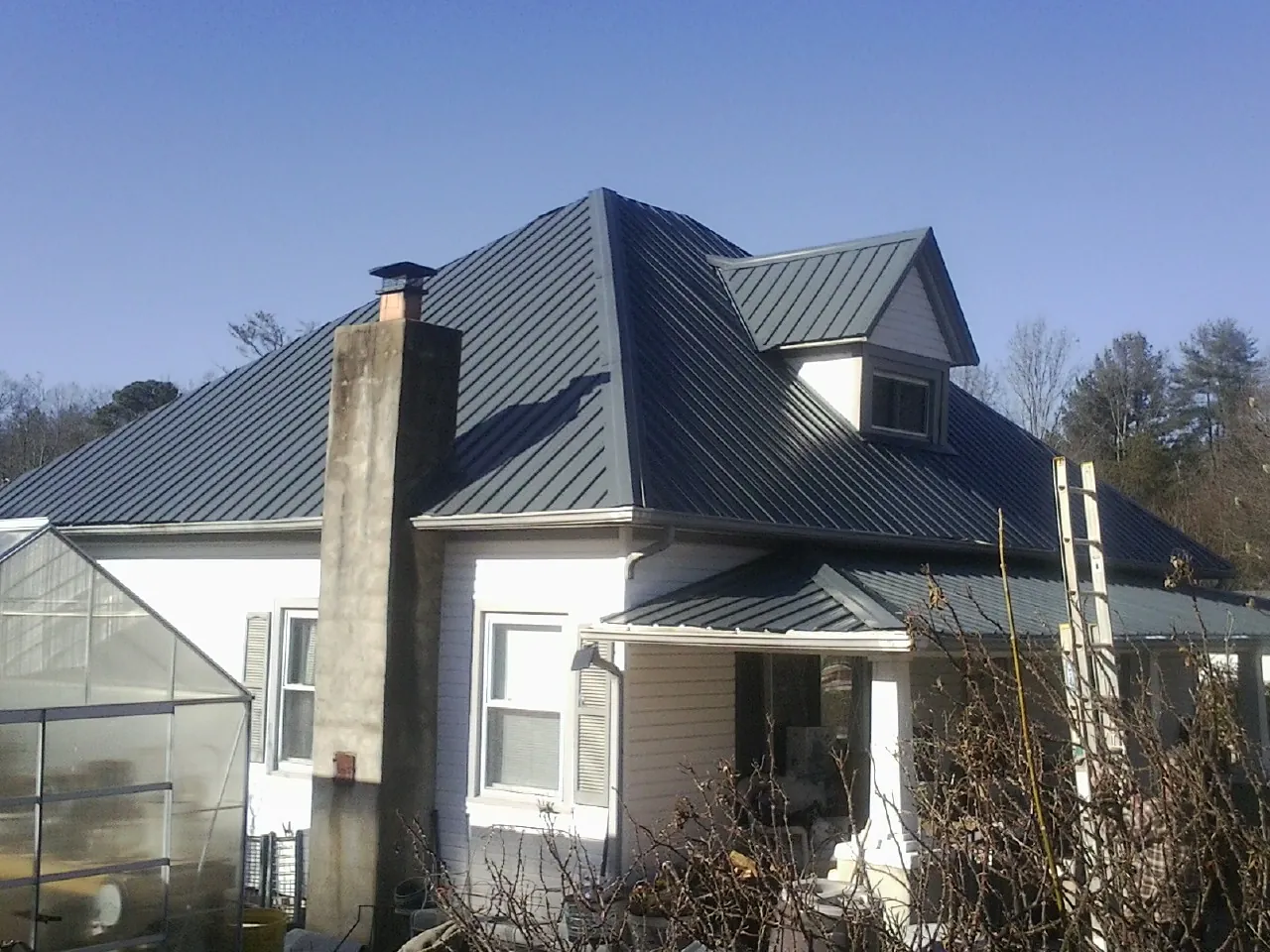 Dark blue standing seam metal roof on a white farmhouse with dormer — Slate & Tile Roof Repair by Roofing Brothers in Chino