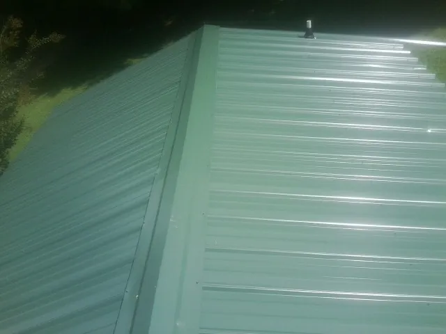 New green metal panels meeting at the ridge of a roof — Flat Roof Repair work by our crew in Chino