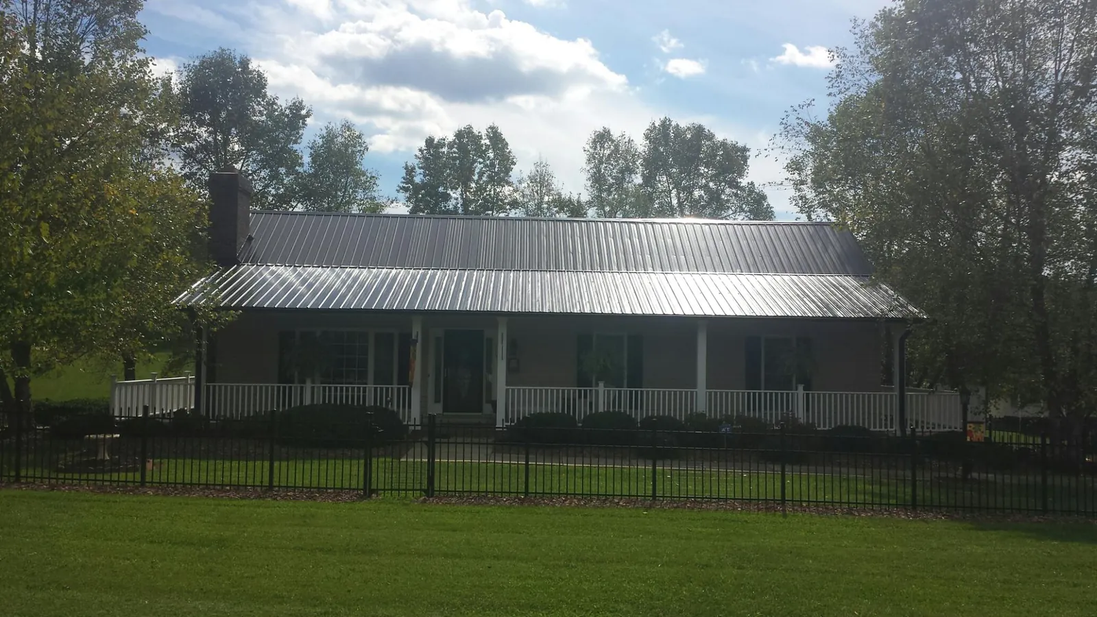 Gray metal roof on a brick ranch with a full width front porch — Gutter Guard Installation work by our crew in Chino
