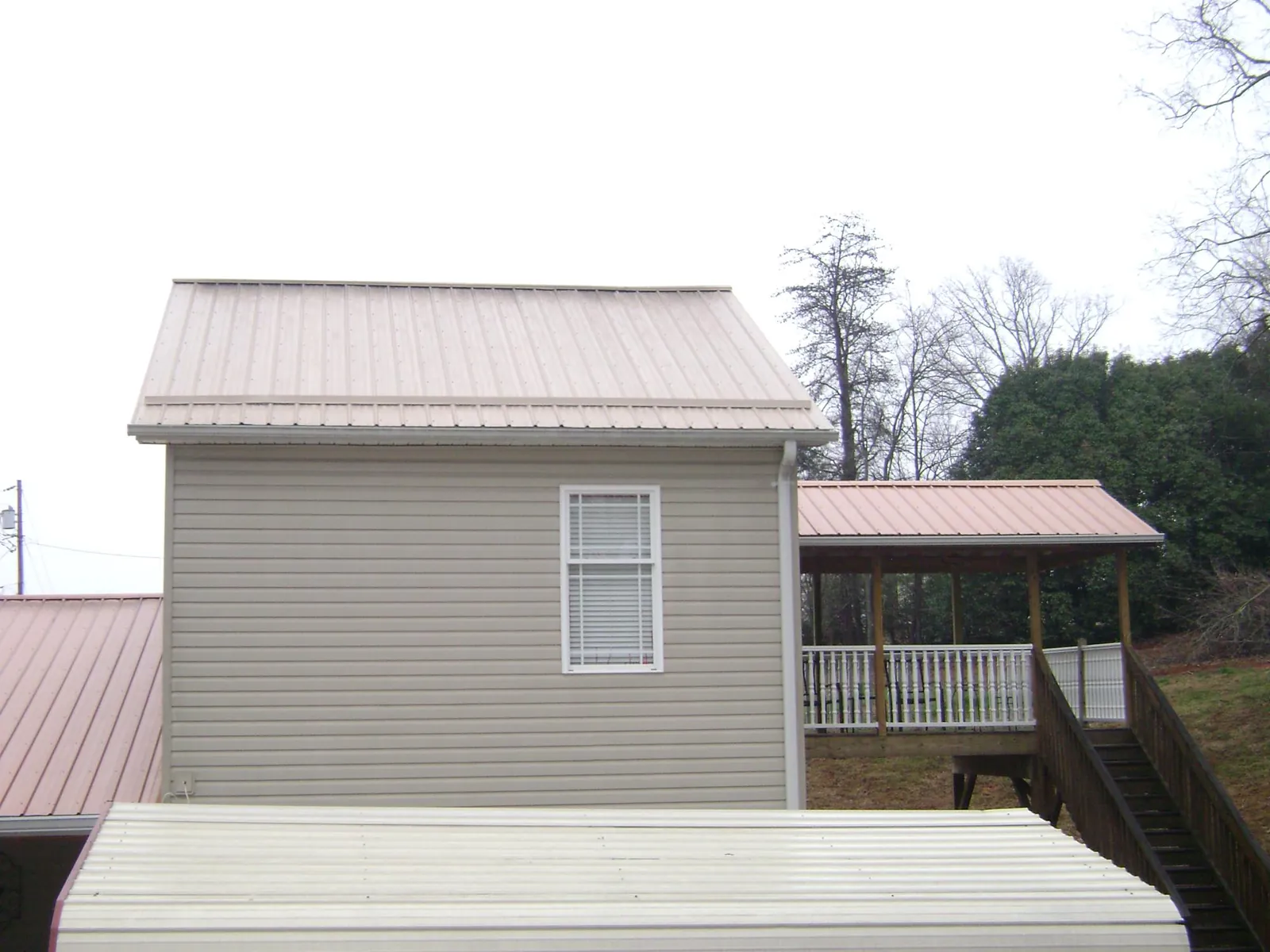 Tan metal roofs on a two story addition and attached porch, from a Roof Replacement job in Chino